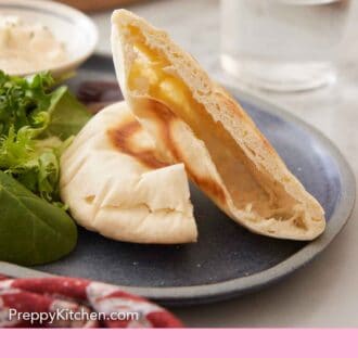 Pinterest graphic of a plate showing a pita bread cut in half, showing the air pocket.