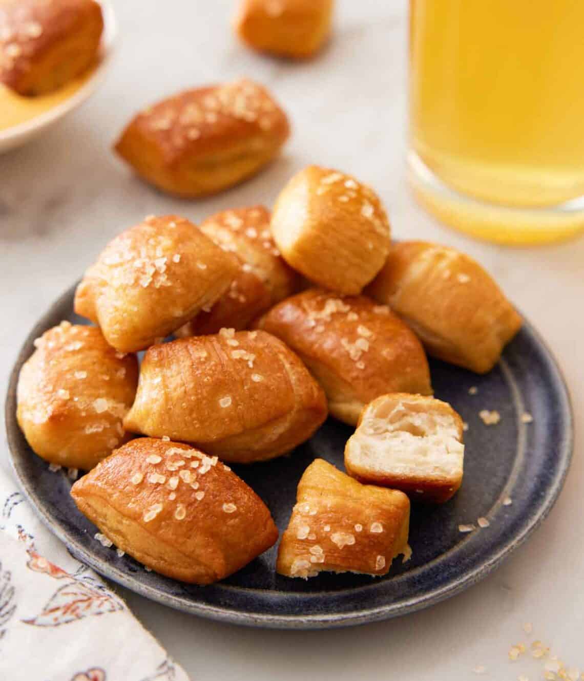 A plate with a handful of pretzel bites with one torn in half, showing the middle.