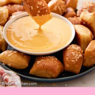 Pinterest graphic of a platter of pretzel bites with one being dipped and lifted up.