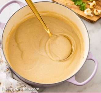 Pinterest graphic of an overhead view of a dutch oven with cauliflower soup and a ladle inside.