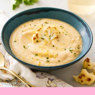 Pinterest graphic of a bowl of cauliflower soup topped with parsley, lemon zest, and a roasted cauliflower floret.