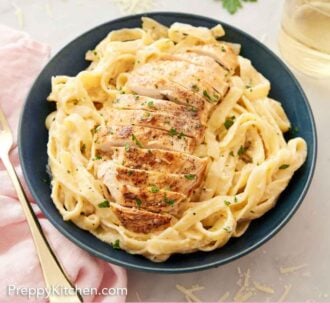 Pinterest graphic of a bowl of chicken alfredo garnished with parsley with parmesan and more parsley scattered in the back.