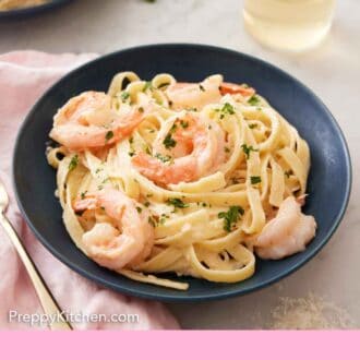 Pinterest graphic of a plate of shrimp Alfredo with a glass of wine in the background along with another plate of pasta.