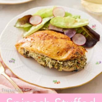 Pinterest graphic of a plate with a spinach stuffed chicken breast with some salad beside it and a glass of wine in the background.