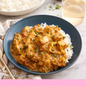 Pinterest graphic of a bowl of chicken curry over rice with a glass of wine and a plate of rice in the back.