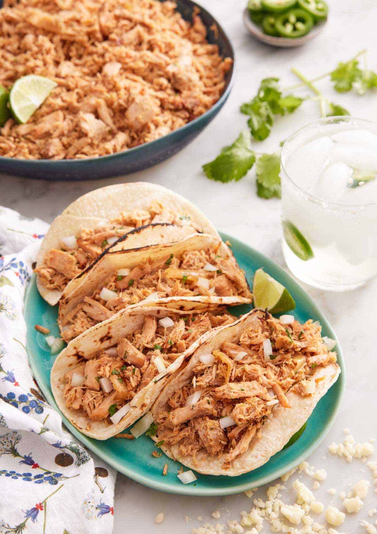 A plate with four tortillas filled with slow cooker carnitas.
