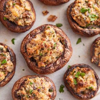 Overhead view of multiple stuffed mushrooms with chopped parsley garnish on top.