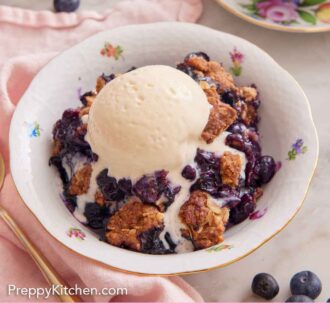 Pinterest graphic of a bowl of blueberry crisp with a scoop of vanilla ice cream on top, melting into it.