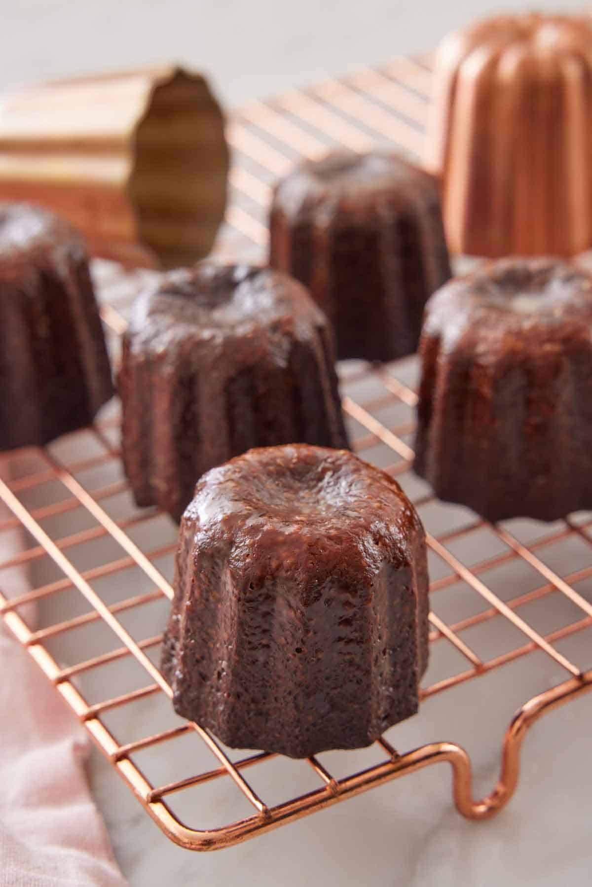 Multiple canelés on a rose-gold wire cooling rack.