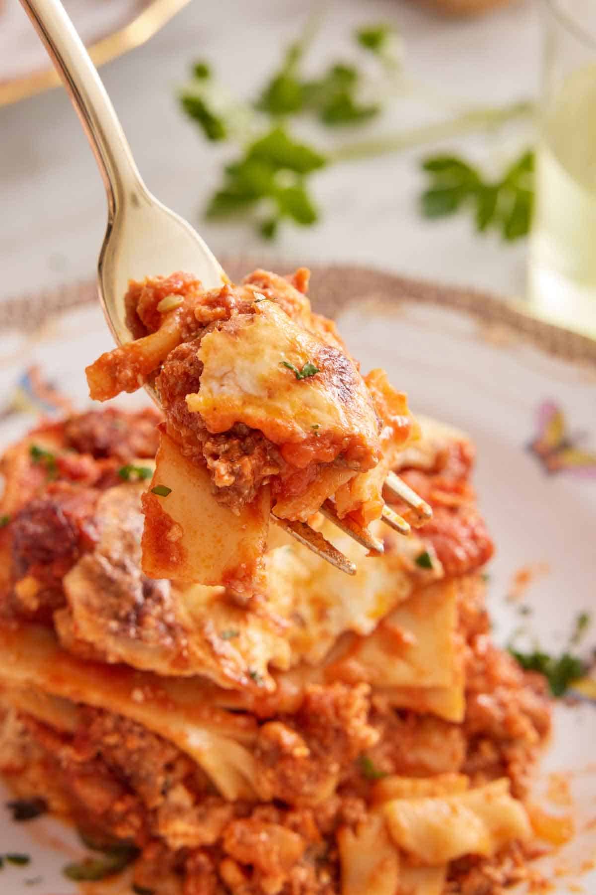 A forkful of lasagna lifted from a plated serving.