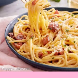 Pinterst graphic of a forkful of pasta carbonara lifted from the plate.