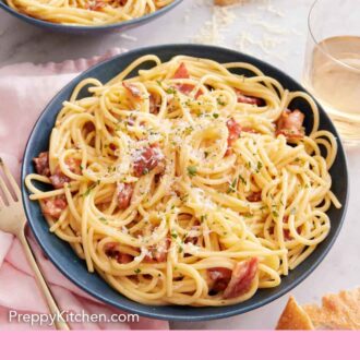 Pinterest graphic of a plate of pasta carbonara with parmesan sprinkled on top with a glass of wine, block of parmesan, and another plate in the background.