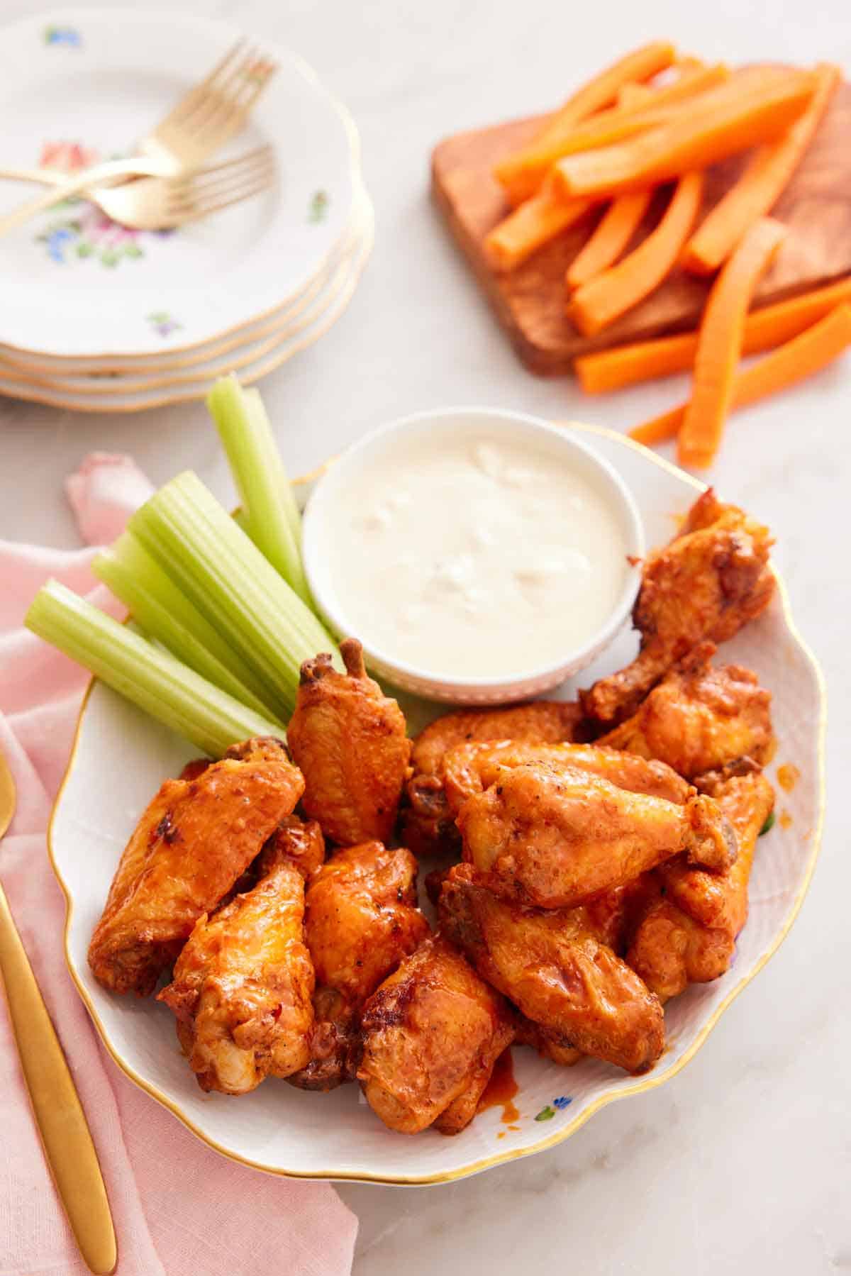 A platter of multiple air fryer chicken wings with dip and celery sticks.