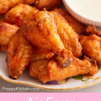 Pinterest graphic of a close view of air fryer chicken wings tossed in a buffalo sauce with a bowl of dip.