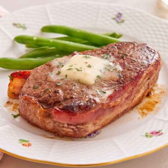 A plate of bacon wrapped filet mignon with green beans.