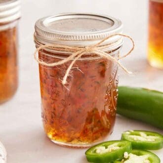 Multiple mason jars of jalapeno jelly with twine tied around the front jar.