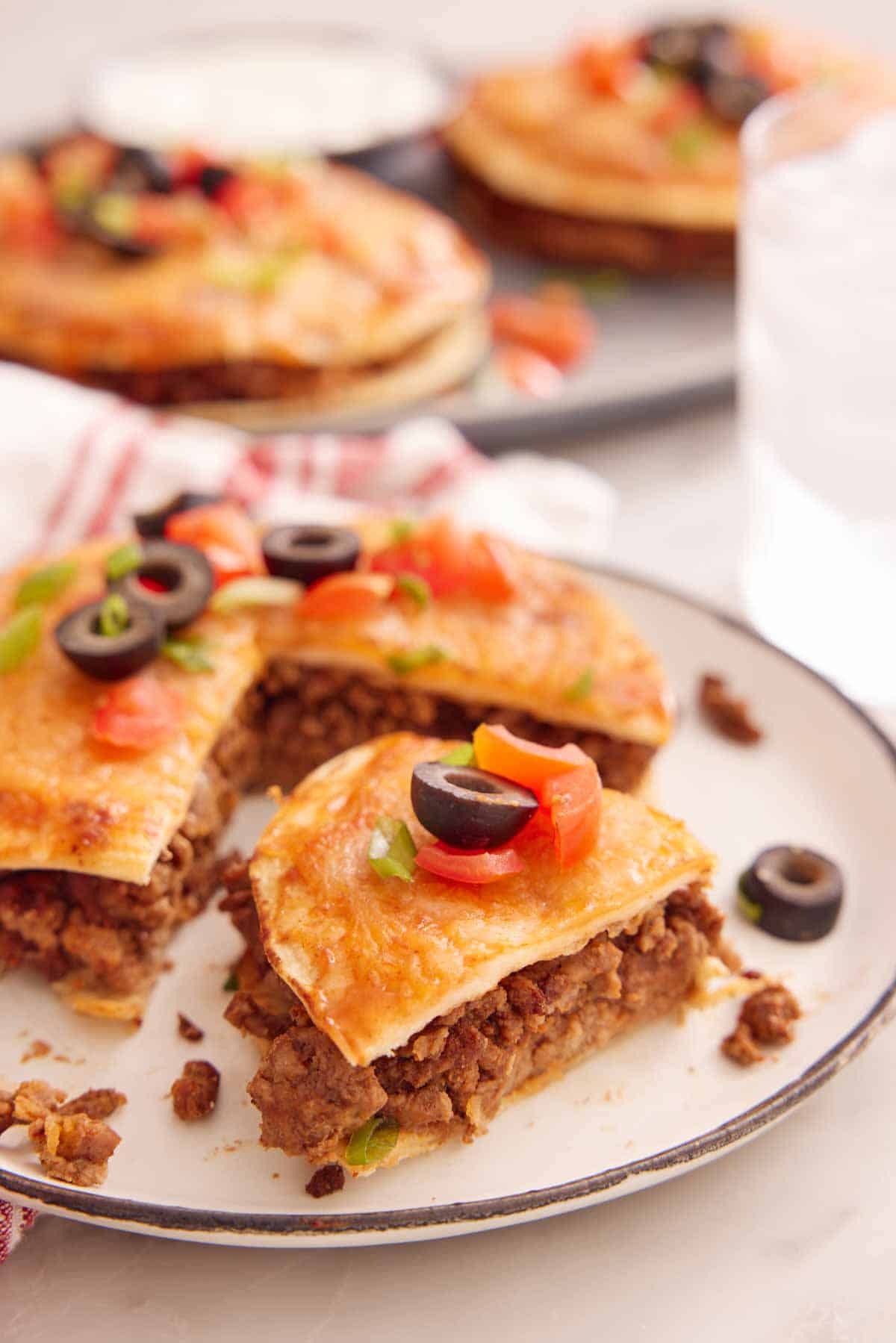 A close up view of a plate of a Mexican pizza with a slice cut, slightly pulled forward.