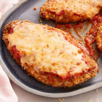 Close up view of one of three air fryer chicken parmesan on a platter.