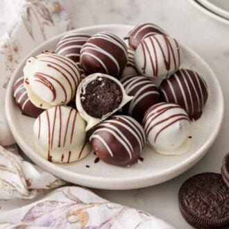 A plate with a pile of Oreo balls with one in the middle with a bite taken out, showing the interior.