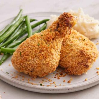 A plate with two pieces of oven fried chicken with green onions and mashed potatoes.