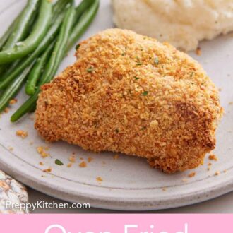 Pinterest graphic of an oven fried chicken thigh on a plate with some green beans and mashed potatoes.