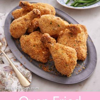 Pinterest graphic of an oval platter of oven fried chicken with plates of green beans and mashed potatoes in the background.