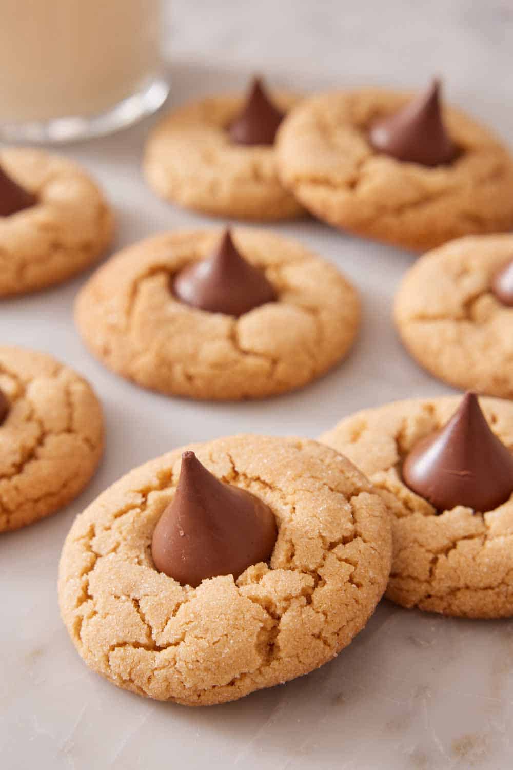 Multiple peanut butter blossoms on a marble surface with one slightly stacked on top of another.