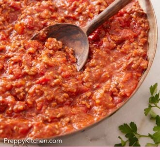Pinterest graphic of a skillet of spaghetti sauce with a wooden serving spoon tucked in.