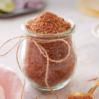 Pinterest graphic of a small jar of taco seasoning with a string bow tied on.