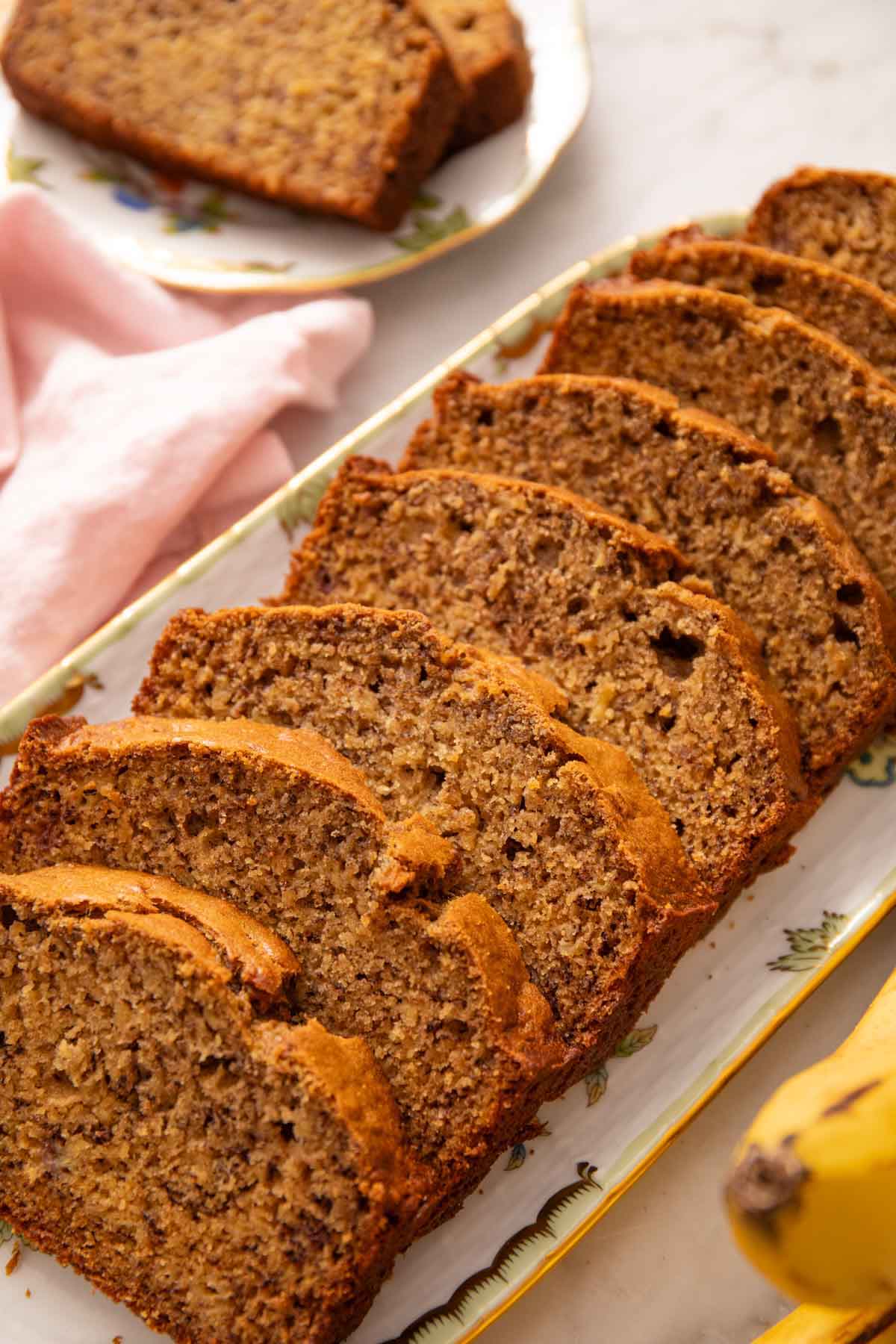 A platter with a loaf of sliced banana bread.