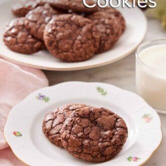 Pinterest graphic of a plate with two brownie cookies with a cup of milk and platter of more cookies in the background.