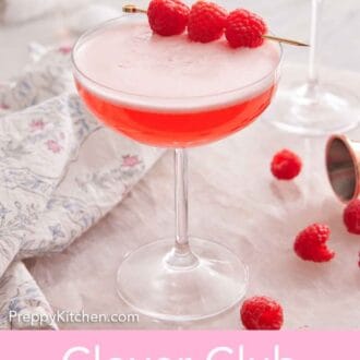 Pinterest graphic of Clover Club Cocktail with raspberries as a garnish and on the counter. A second cocktail in the background.