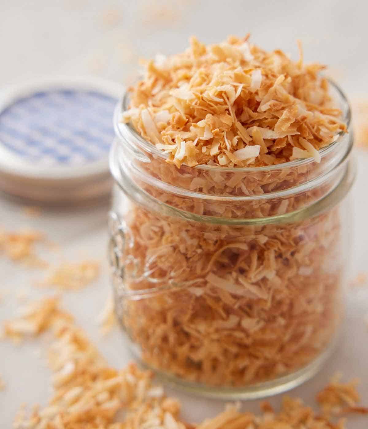 A close up view of a mason jar of toasted coconut.