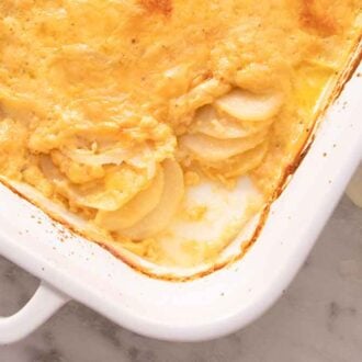 Overhead view of a casserole dish of cheesy potatoes au gratin with the corner serving scooped out.