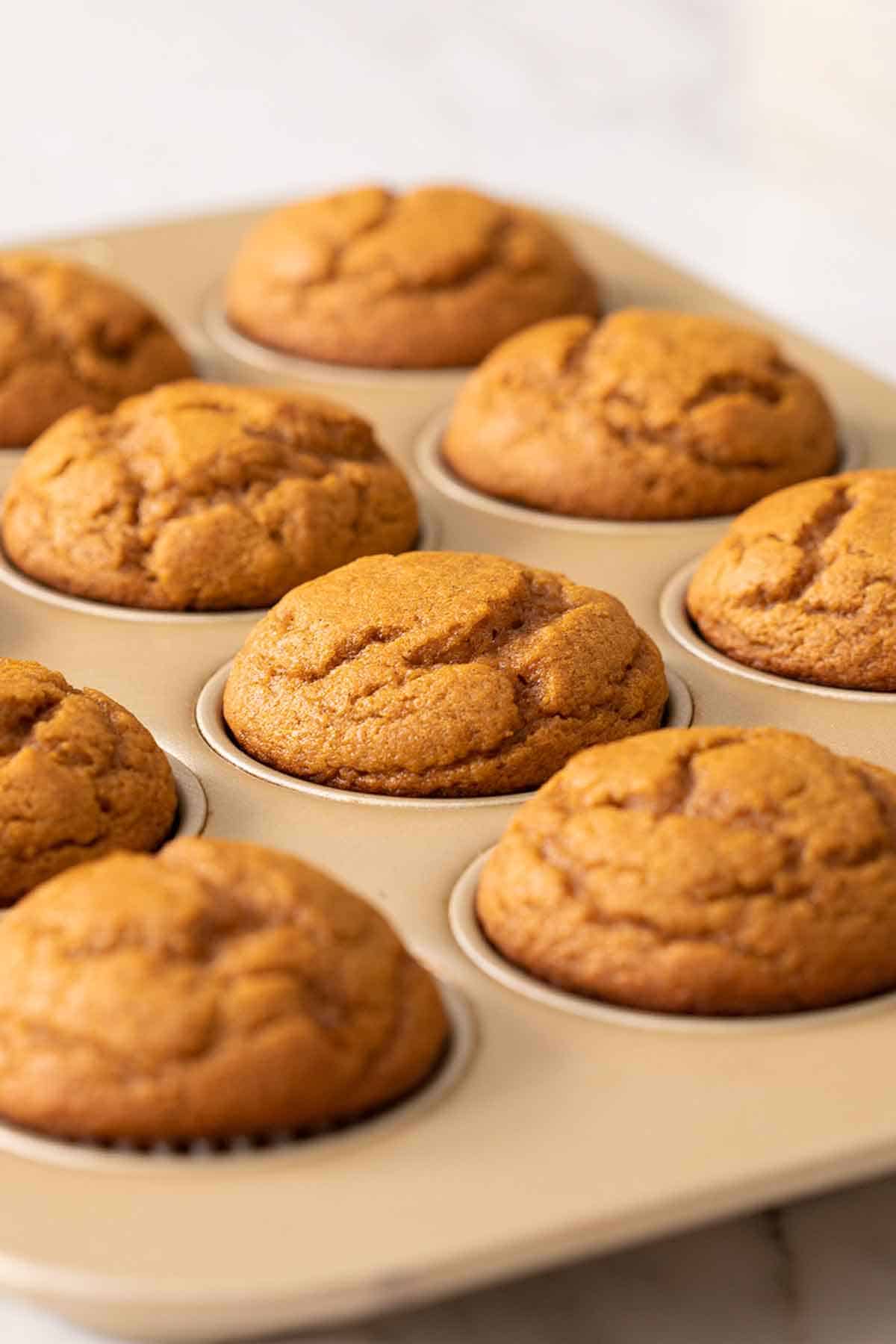 A muffin tin full of pumpkin muffins.