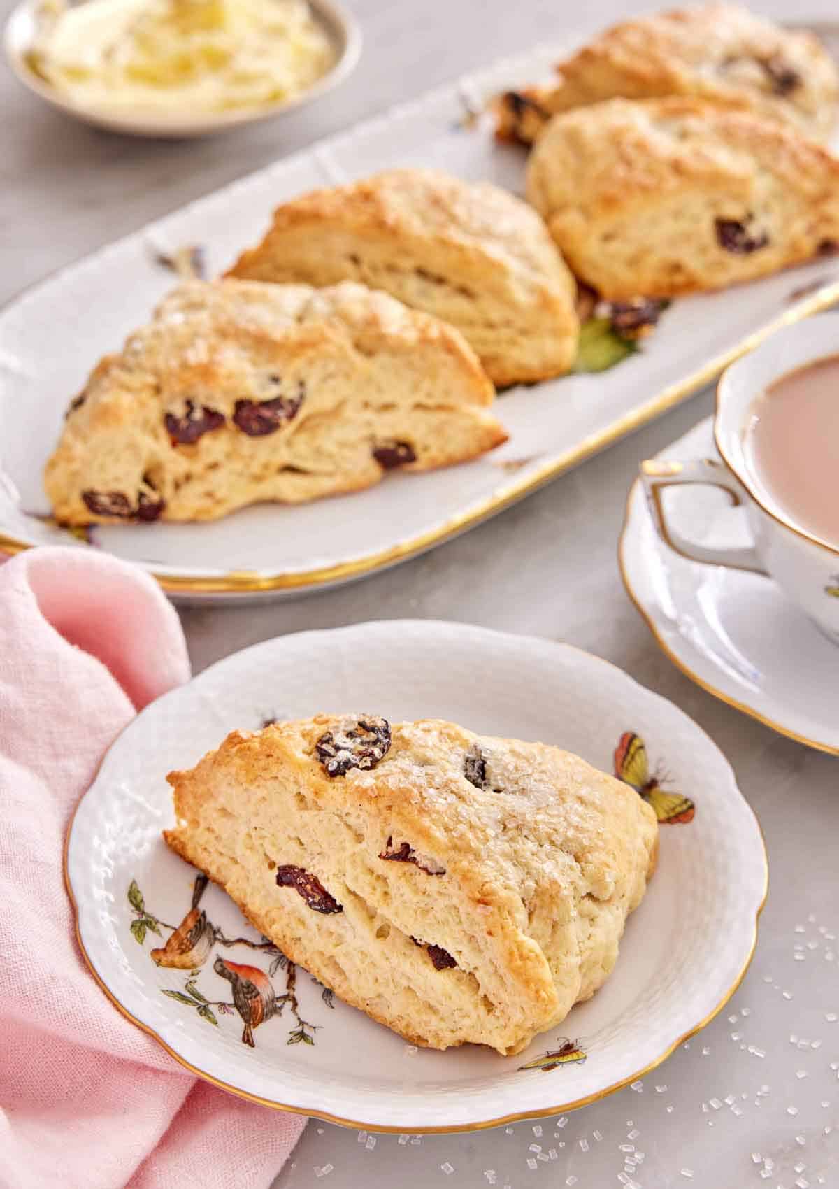 A plate with a scone studded with dried cranberries with additional scones in the background.