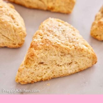 Pinterest graphic of a scone topped with coarse sugar with more scones in the background.