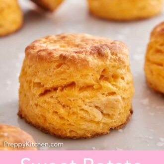 Pinterest graphic of a sweet potato biscuit on a marble counter with additional biscuits in the background.