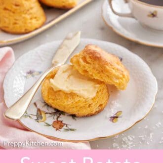 Pinterest graphic of a plate with a sweet potato biscuit cut in half with butter spread on the cut-side. Coffee in the background and more biscuits on a platter.