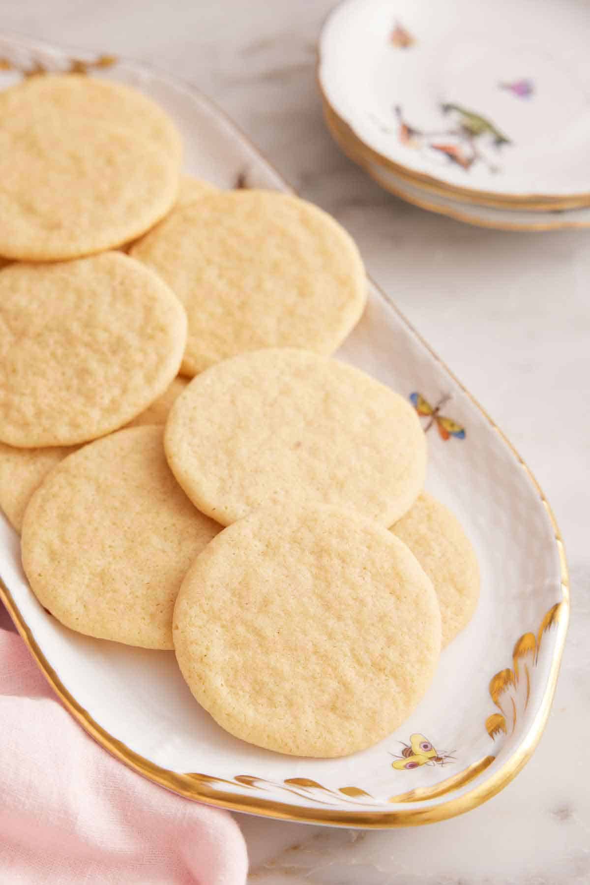 A platter of tea cakes with some plates in the background.