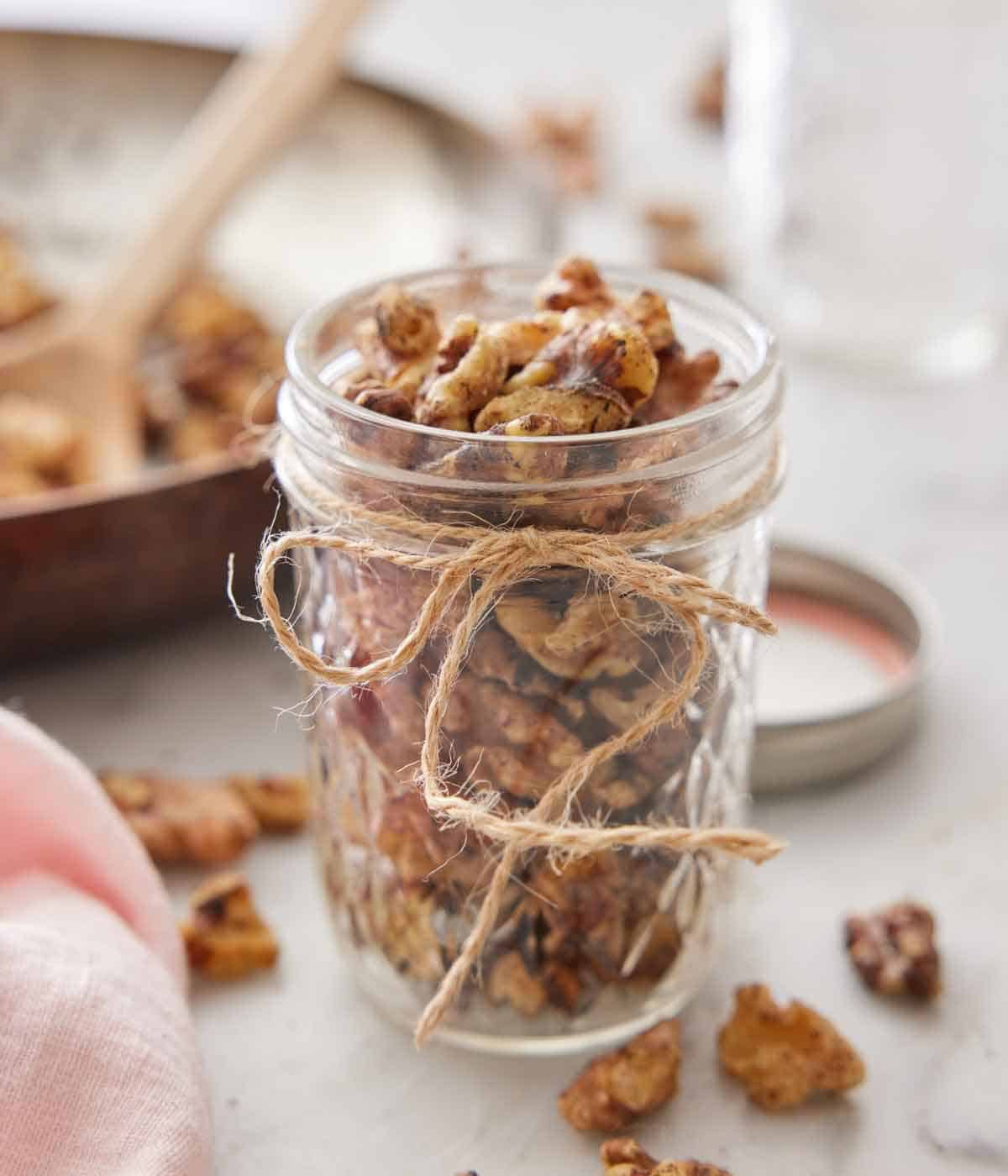 A mason jar of toasted walnuts with a twine bow.