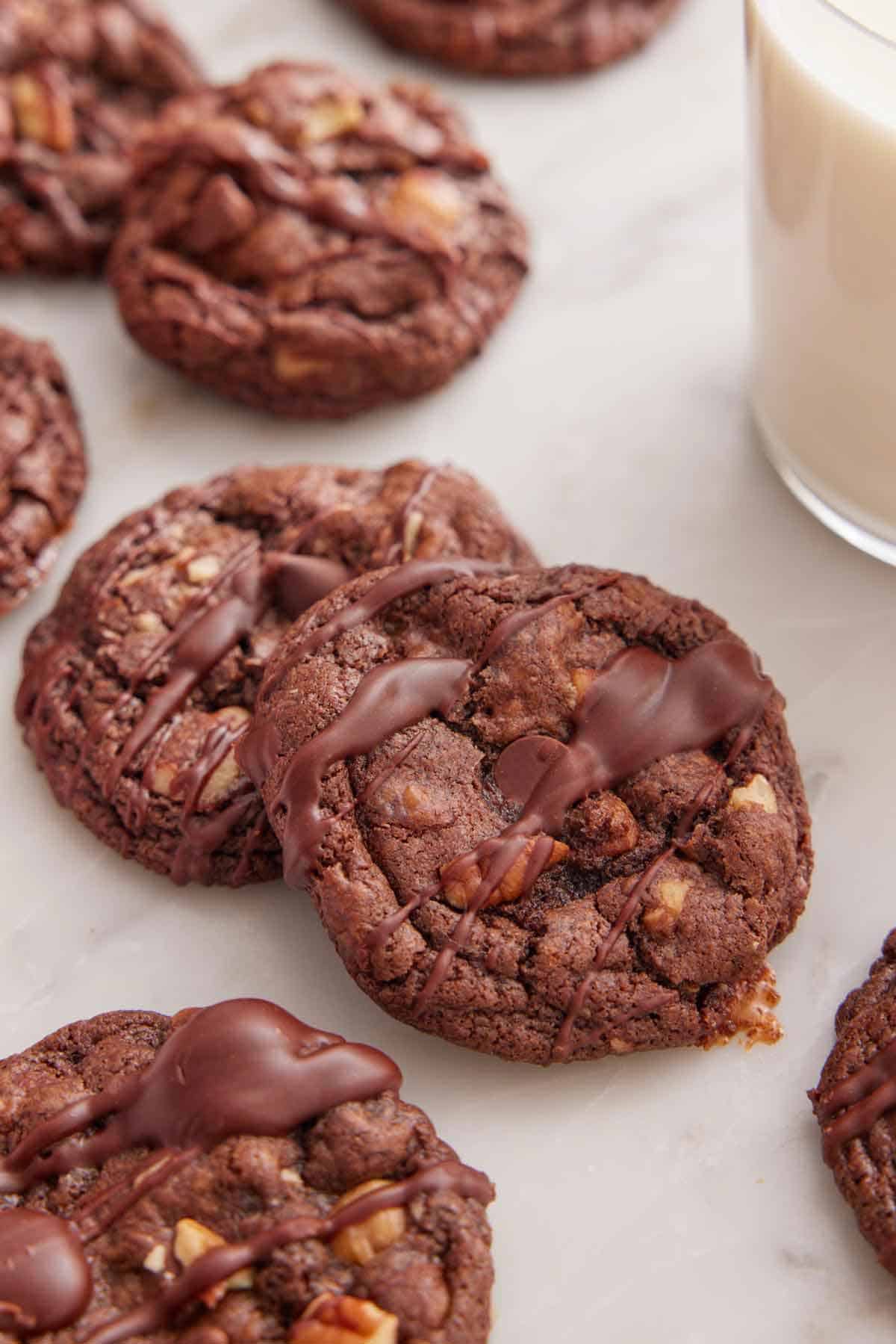 Multiple turtle cookies on a marble surface with a glass of milk.