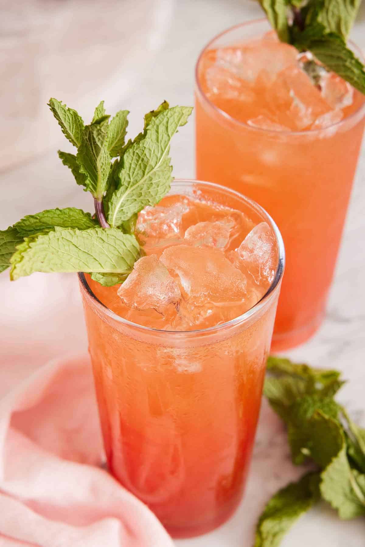 A slightly angled view of two glasses of zombie cocktails with mint garnishes and more mint on the counter.
