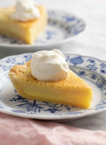 Two slices of buttermilk pie on blue and white plates. One in the background out of focus.