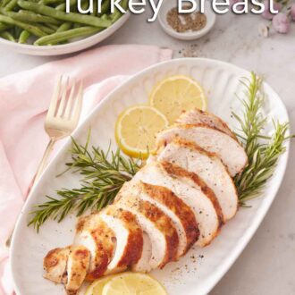 Pinterest graphic of a platter with a sliced air fryer turkey breast on top of rosemary and lemon slices. A plate of green beans in the background.
