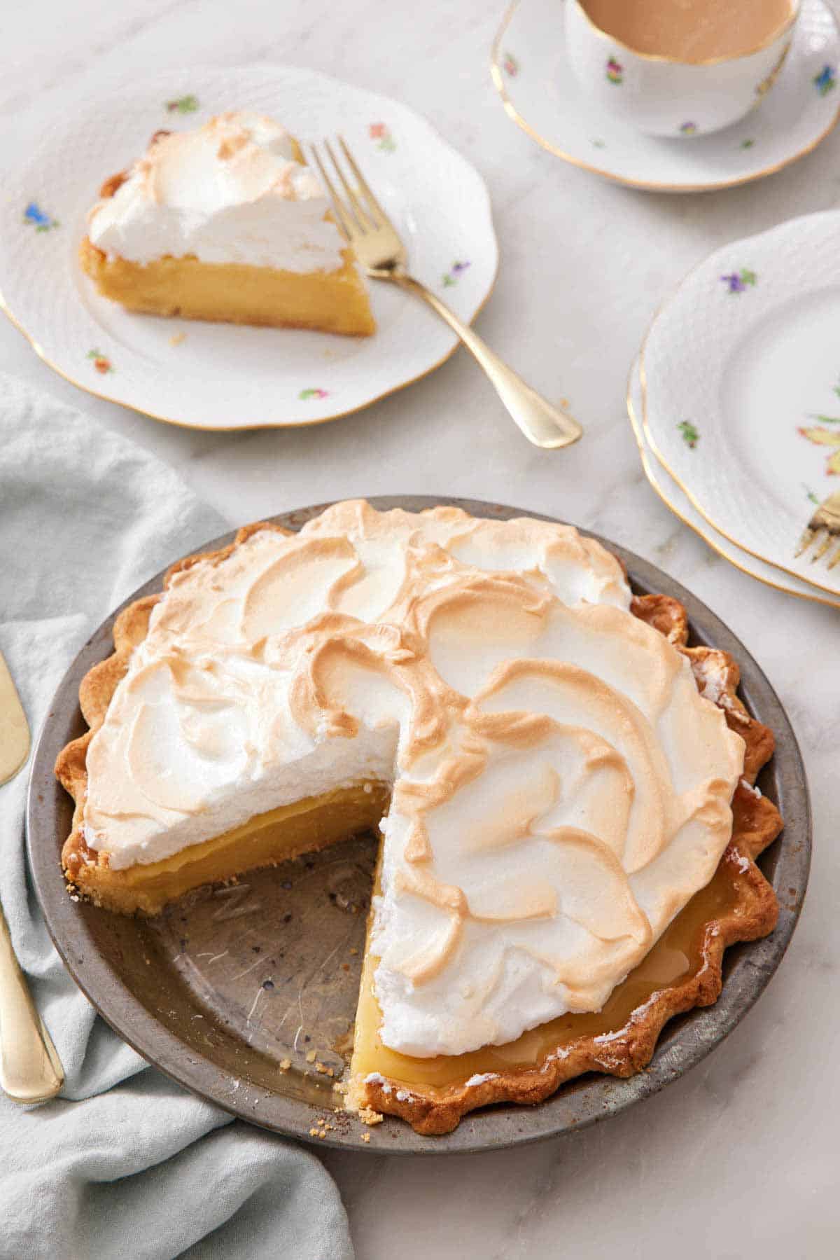A baking dish of butterscotch pie with a slice cut out and plated in the background.