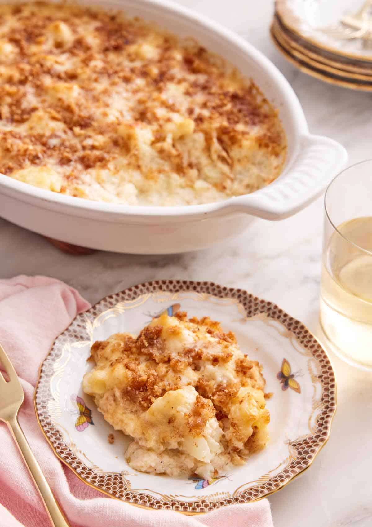 A plate of cauliflower gratin with a baking dish in the background.