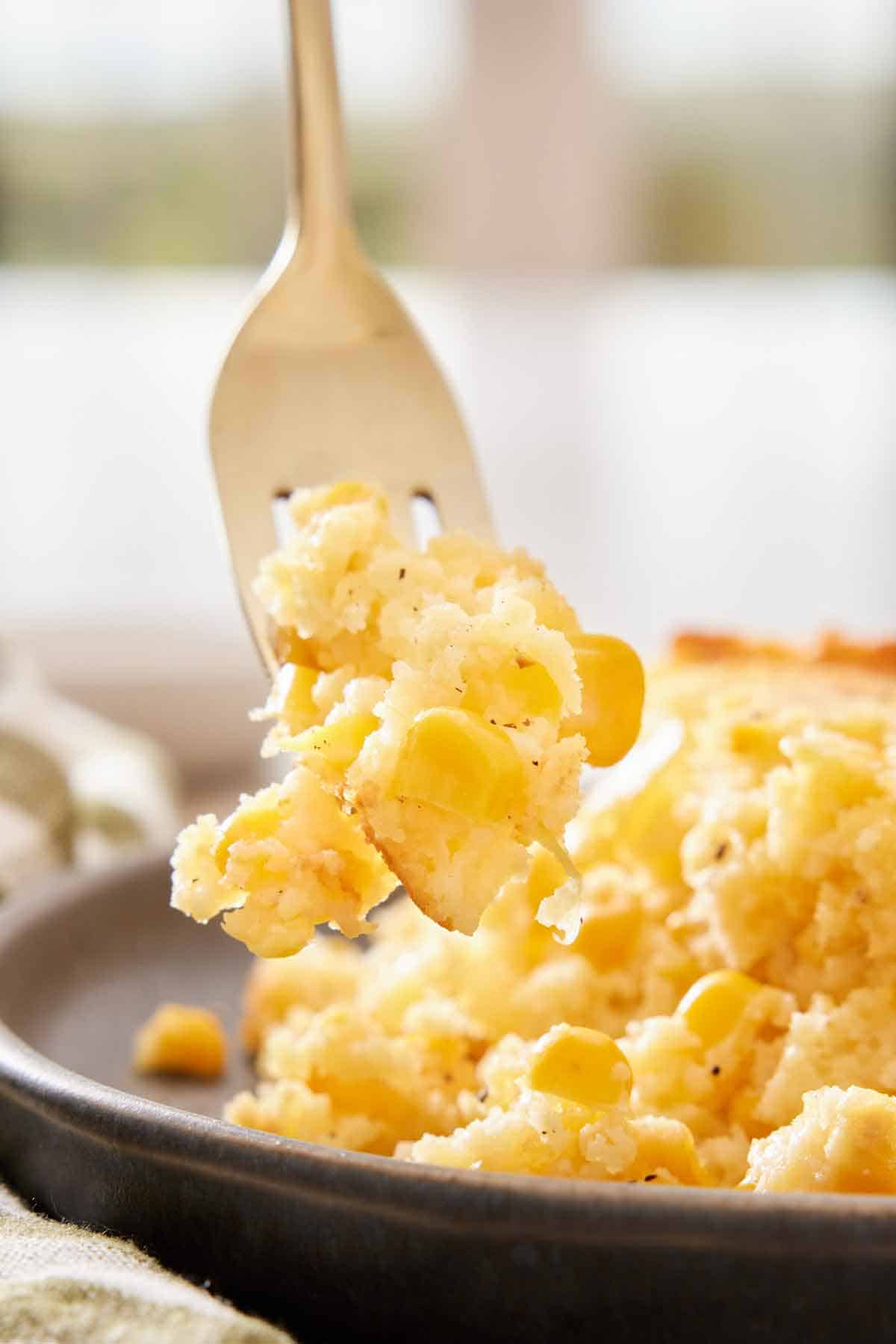 A forkful of corn casserole lifted from a plate.