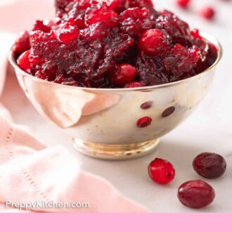 Pinterest graphic of a bowl of cranberry sauce with some cranberries scattered around.