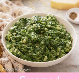 Pinterest graphic of a bowl of creamed spinach with a block of grated parmesan, stack of plates, and forks in the background.